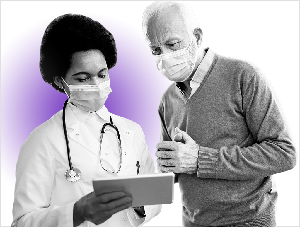 African American female doctor and her senior patient using digital tablet while wearing protective face mask at hospital hallway.